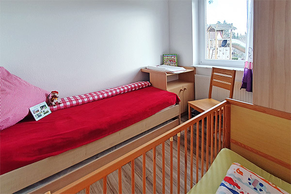 Schlafzimmer mit Kinderbett und Wickeltisch