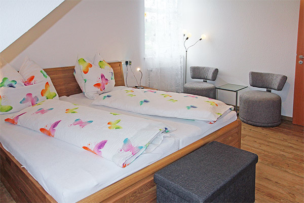 Schlafzimmer mit Doppelbett, Babybett und kleiner Sitzecke