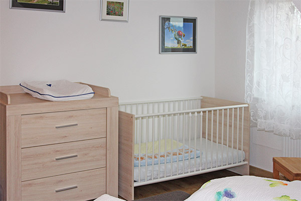 Schlafzimmer mit Doppelbett, Babybett und kleiner Sitzecke